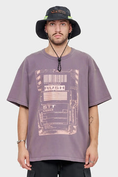 Mężczyzna w fioletowej koszulce z nadrukiem bagażowym i czarnym kapeluszu typu bucket hat