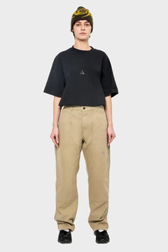 Osoba w czarnej koszulce oversize, beżowych luźnych spodniach i czapce beanie, styl streetwear