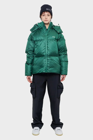 Osoba w zielonej puchowej kurtce Arte, czarnej czapce i czarnych spodniach cargo, styl streetwear