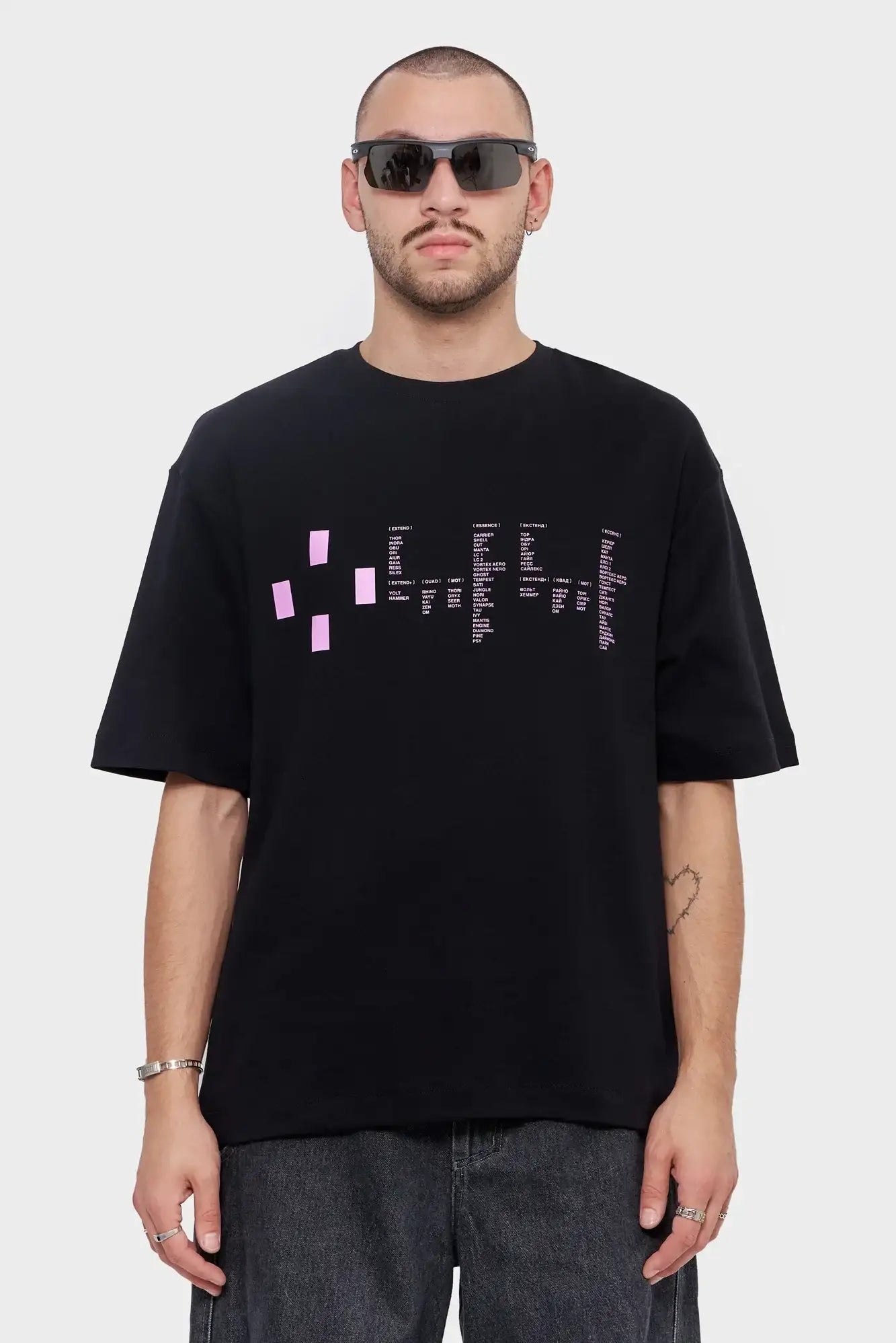 Mężczyzna w czarnym t-shircie z różowym nadrukiem i w okularach przeciwsłonecznych