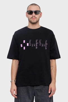 Mężczyzna w czarnym t-shircie z różowym nadrukiem i w okularach przeciwsłonecznych