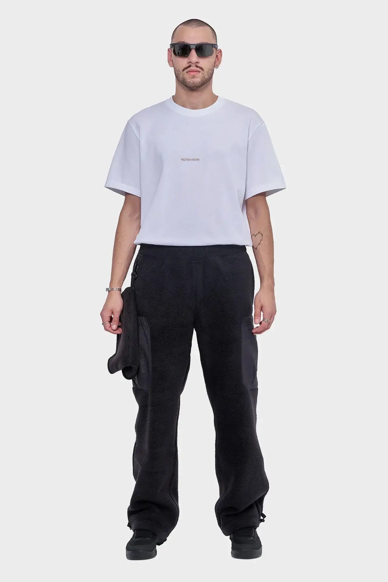 Mężczyzna w białej koszulce z logo i czarnych spodniach polarowych, styl streetwear