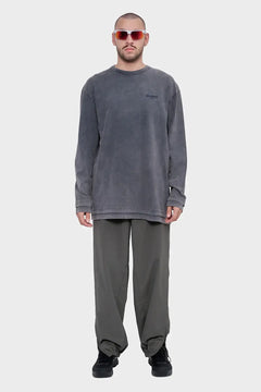 Mężczyzna w szarych okularach, dresowej bluzie z napisem 'Silence' i luźnych oliwkowych spodniach