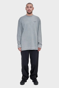 Model w szarym longsleeve z napisem Silence, czarne spodnie, sneakersy, minimalistyczny styl uliczny