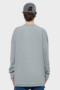 Szara bluza oversize z długim rękawem, model z tyłu, jeansowa czapka, styl streetwear
