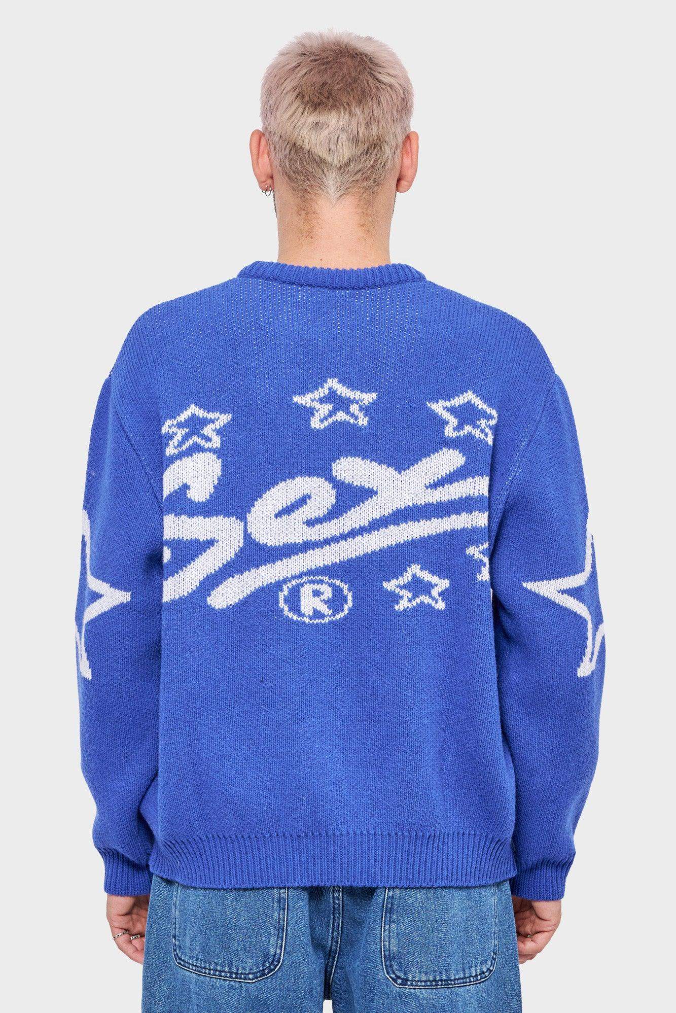 Mężczyzna w niebieskim swetrze z białym napisem i gwiazdkami na plecach, modna odzież streetwear
