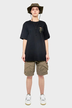 Osoba w czarnym t-shircie, khaki krótkich spodenkach cargo, bucket hat i sneakersach