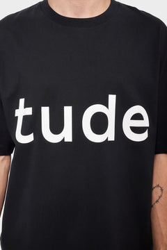 Czarna koszulka z białym napisem "tude", minimalistyczny styl streetwear