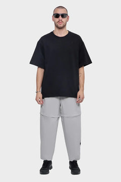 Mężczyzna w okularach przeciwsłonecznych, czarny t-shirt, szare spodnie, modne ubranie streetwear