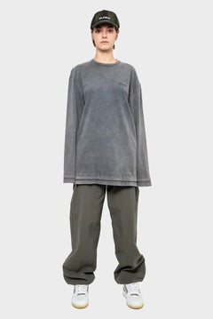 Osoba w szarej czapce z daszkiem, oversize bluza z napisem SILENCE i luźne spodnie, styl streetwear