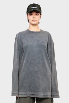 Osoba w czarnej czapce z daszkiem i szarej bluzie z napisem SILENCE, minimalistyczna moda streetwear