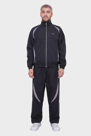 Mężczyzna w czarnym dresie z jasnoszarymi wstawkami i białych sneakersach, moda streetwear