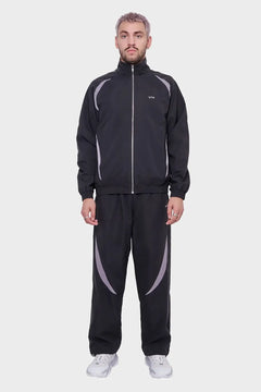 Mężczyzna w czarnym dresie z jasnoszarymi wstawkami i białych sneakersach, moda streetwear
