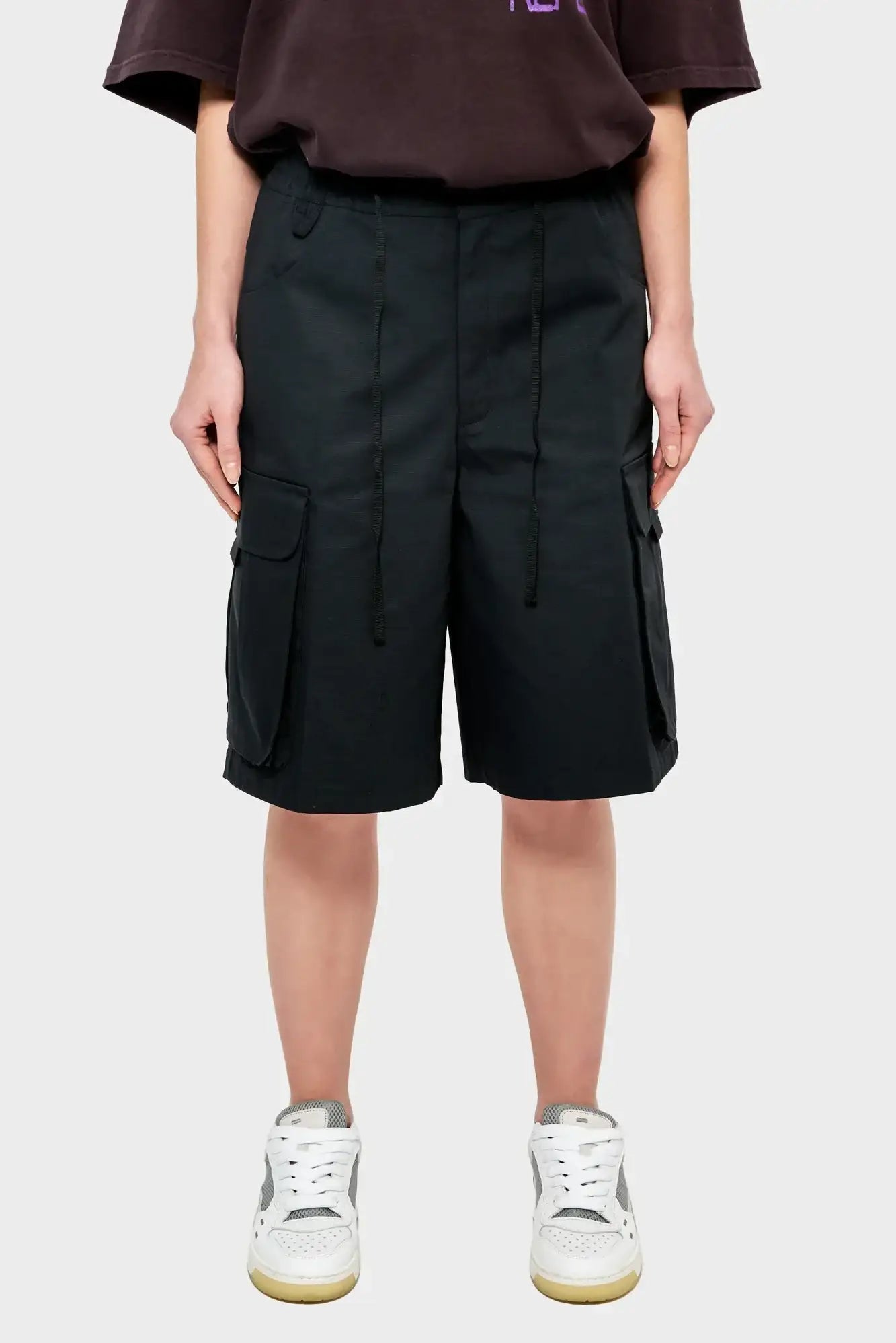 Czarne szorty cargo damskie z kieszeniami, styl streetwear, modelka w sneakersach