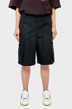 Czarne szorty cargo damskie z kieszeniami, styl streetwear, modelka w sneakersach