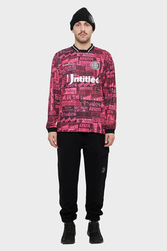 Mężczyzna w czarnej czapce i różowej bluzie z nadrukami, czarne spodnie cargo, styl streetwear