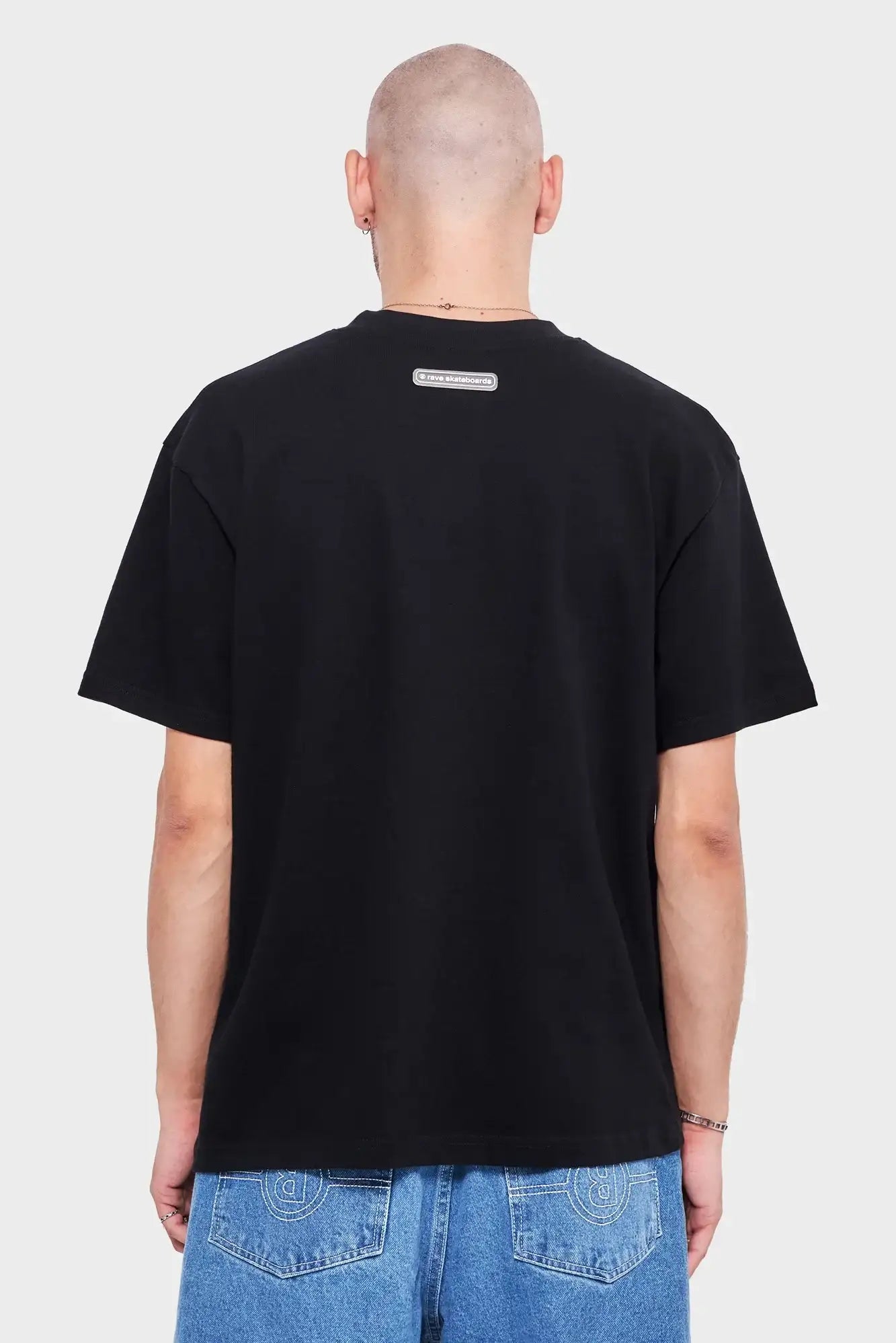 Czarna koszulka z logo na plecach, krótkie rękawy, męska moda streetwear, denimowe jeansy.