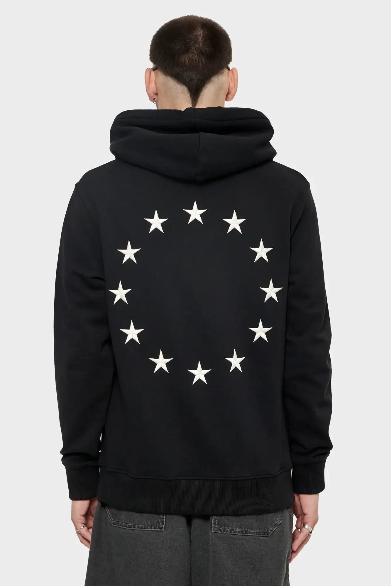 Czarna bluza z kapturem, białe gwiazdy w okręgu na plecach, styl streetwear męski.