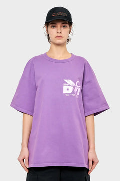 Kobieta w fioletowym oversize t-shircie z nadrukiem i czarnej czapce z daszkiem, moda streetwear