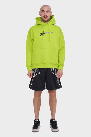 Mężczyzna w neonowej zielonej bluzie z kapturem i czarnych sportowych szortach, styl streetwear