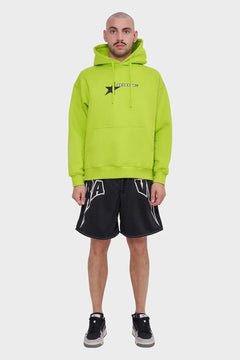 Mężczyzna w neonowej zielonej bluzie z kapturem i czarnych sportowych szortach, styl streetwear