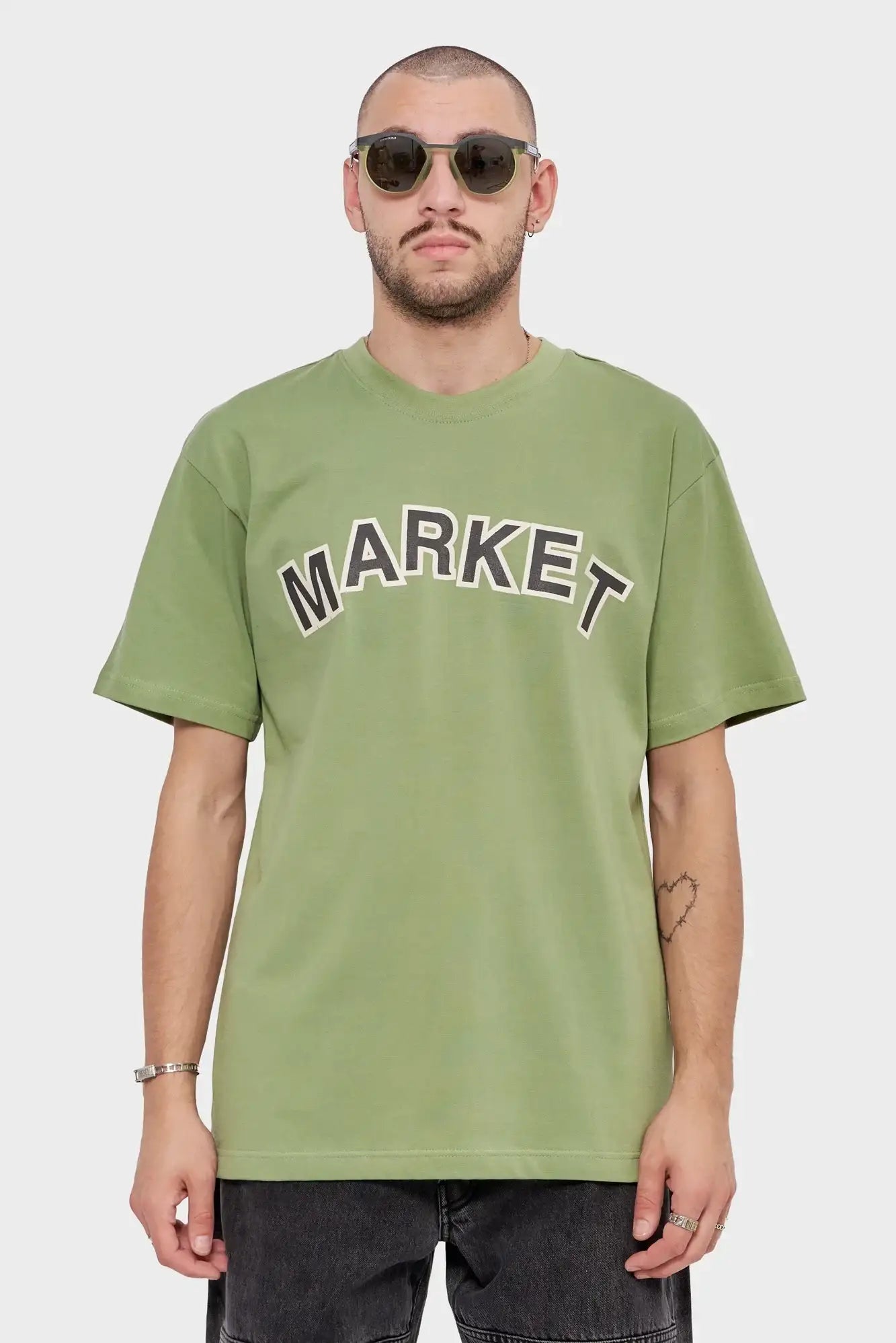 Mężczyzna w zielonej koszulce MARKET, okulary przeciwsłoneczne, casualowy styl