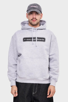 Mężczyzna w szarej bluzie z kapturem rave skateboards i czapce z daszkiem, styl streetwear