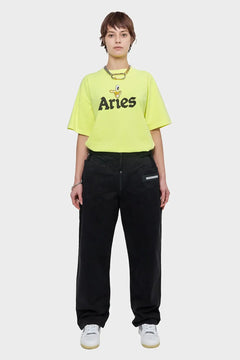Modelka w żółtym t-shircie Aries z nadrukiem i czarnych luźnych spodniach streetwear