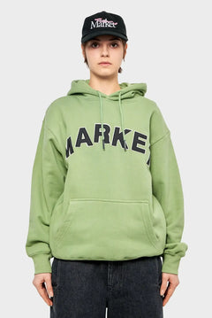 Modelka w zielonej bluzie z kapturem Market, czarna czapka z daszkiem, styl streetwear