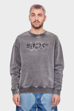 Mężczyzna w szarej bluzie z napisem SFX i dżetami, modne jeansy, styl streetwear