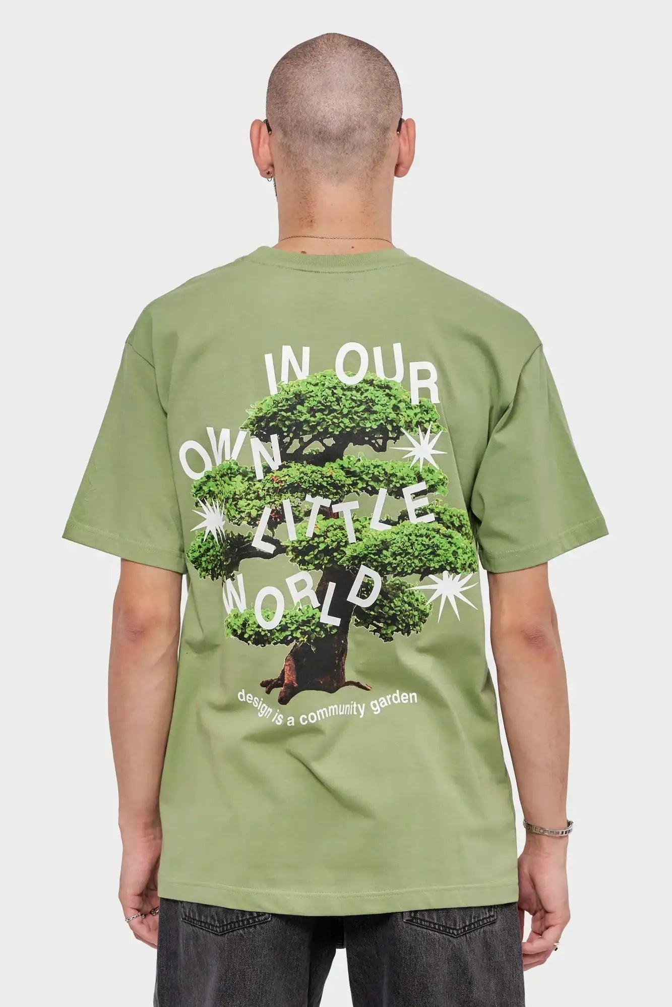 Mężczyzna w zielonej koszulce z grafiką drzewa i napisem na plecach, moda streetwear
